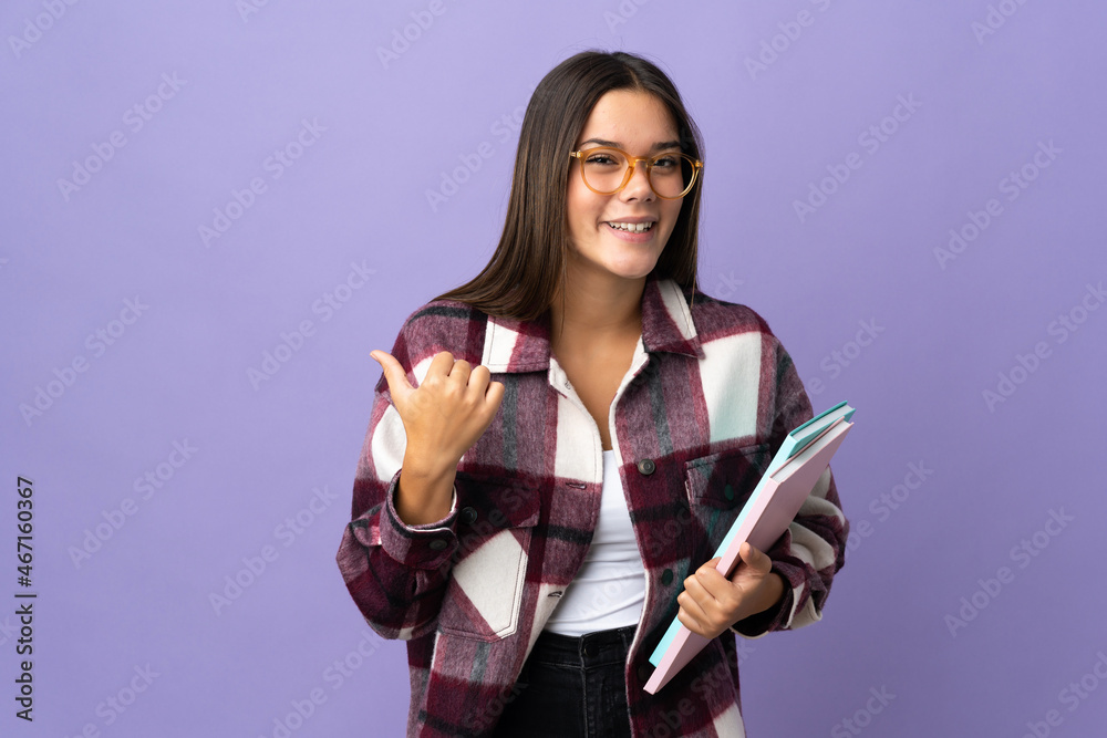 Young student woman isolated on purple background pointing to the side to present a product Young student woman isolated on purple background pointing to the side to present a product
