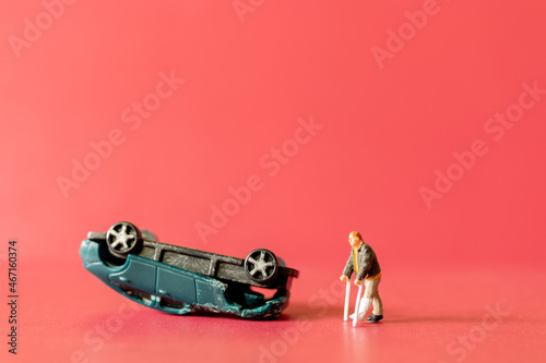 Miniature people broken leg man patient with bandage walking with crutch with toy car wreck ,Safety driving concept photo