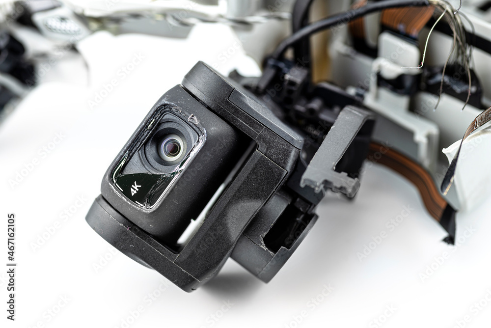 Macro shot of the 4k lens on a damaged drone after a fall with broken cables, isolated on a white background. Macro shot of the 4k lens on a damaged drone after a fall with broken cables, isolated on a white background.