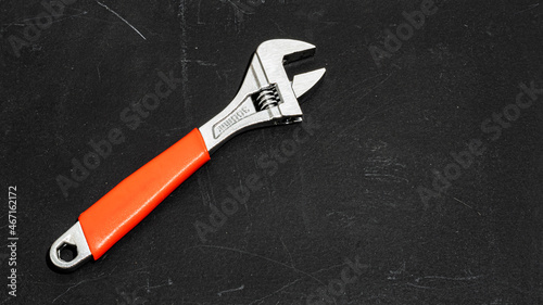 wrench, iron adjustable wrench on a dark background, red rubber handle