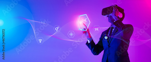 Young man using glasses of virtual reality on dark background. Smartphone using with VR headset,virtual reality,future technology concept.Asian man using VR glasses in colorful neon lights.
 photo