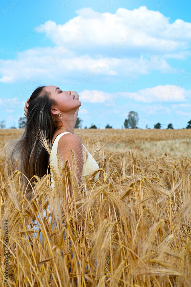Young Asian woman with long hair relaxes in a wheat field Young Asian woman with long hair relaxes in a wheat field