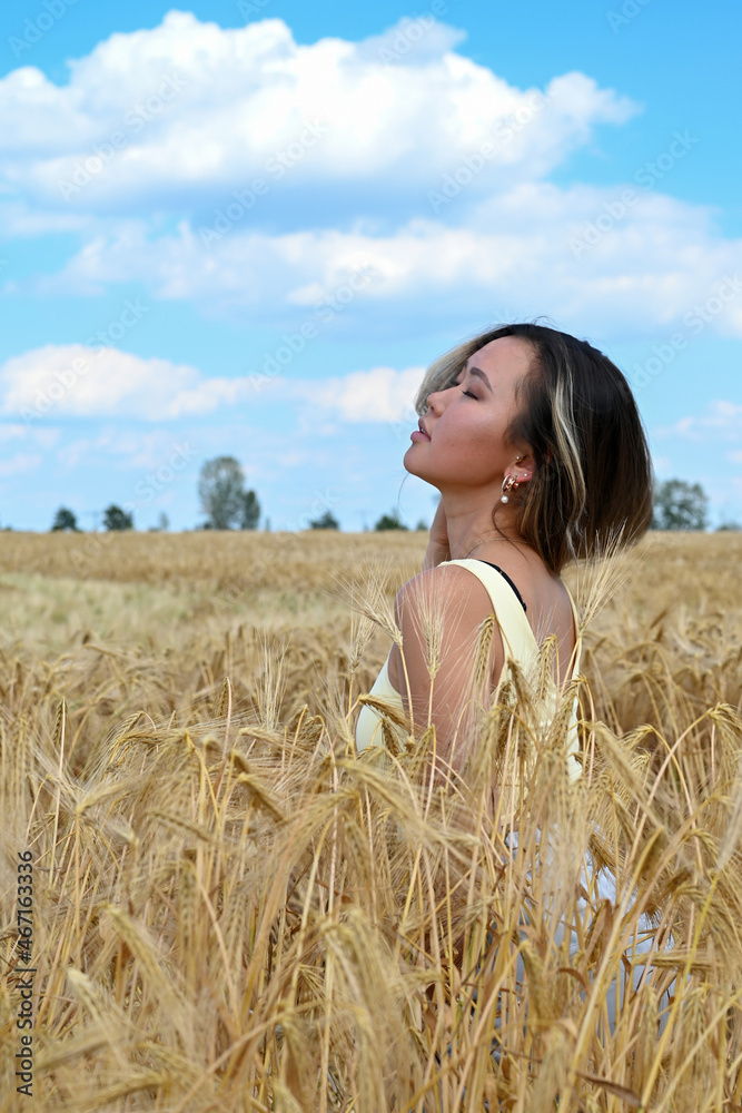 Young Asian woman with long hair relaxes in a wheat field Young Asian woman with long hair relaxes in a wheat field