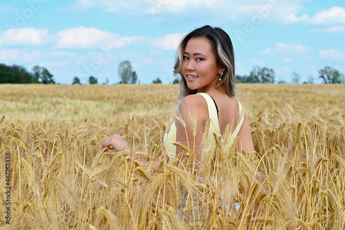 Young smiling asian girl walking in a wheat field