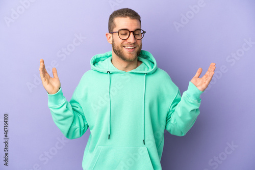 Young handsome caucasian man isolated on purple background smiling a lot © luismolinero