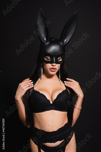 sensual woman in bunny mask and lace lingerie posing isolated on black