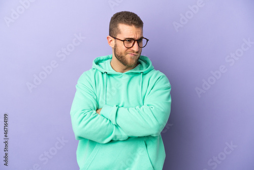 Young handsome caucasian man isolated on purple background with unhappy expression © luismolinero