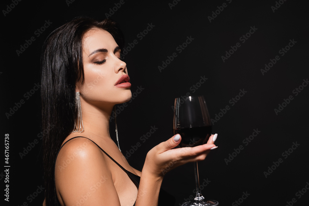 sexy woman with closed eyes holding glass of red wine isolated on black sexy woman with closed eyes holding glass of red wine isolated on black