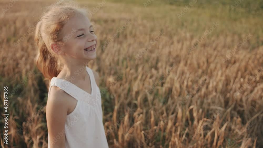 A joyful little girl with missing front teeth fooling around and grimaces at the camera at a family picnic in a wheat field. Slow motion A joyful little girl with missing front teeth fooling around and grimaces at the camera at a family picnic in a wheat field. Slow motion