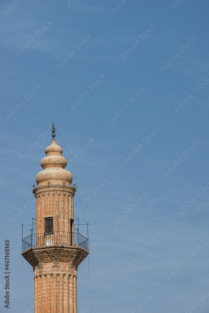 Top of a minaret of ancient Ottoman architecture built with red sandstone with rounded domes and speakers for the call to prayer.