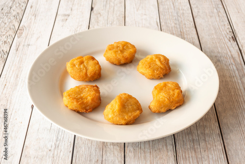 Картината върху платно Fried chicken nuggets battered in flour and egg on white plate