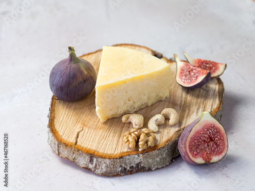 variety of hard cheese with figs and nuts on a wooden cutting board