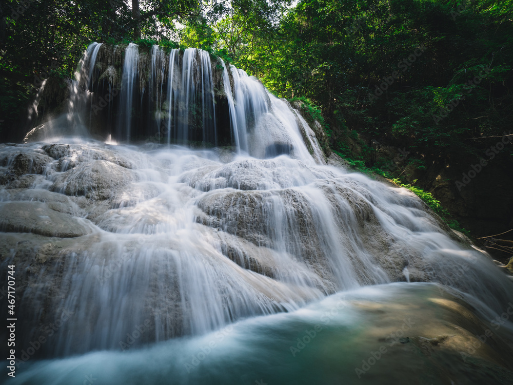 Fototapeta premium Scenic view of Erawan Waterfall. Stunning smooth flowing water stream from limestone cliff with turquoise pond in lush rainforest. Kanchanaburi, Thailand. Long exposure.