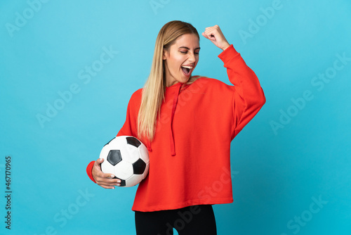 Young football player woman isolated on blue background celebrating a victory