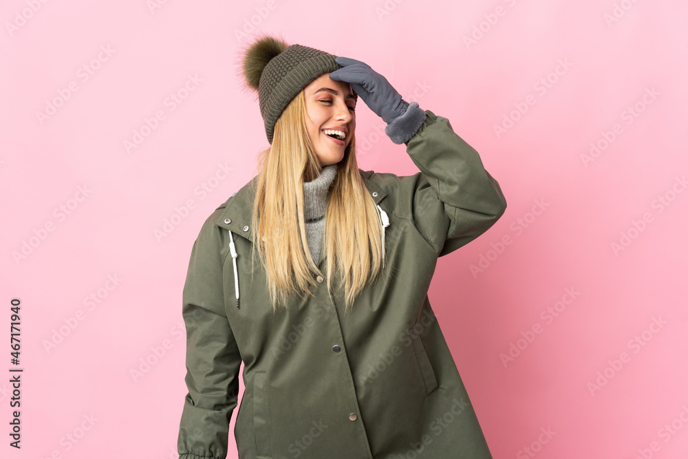 Fototapeta premium Young woman with winter hat isolated on pink background smiling a lot