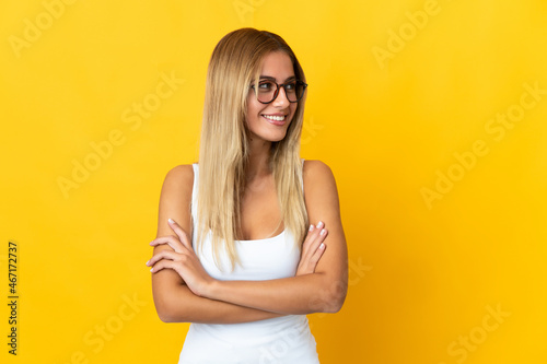 Young blonde woman isolated on yellow background looking to the side © luismolinero