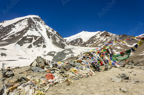 Colorful tibetan Buddhist prayer flags on top of the high altitude pass of Shingo La over the Great Himalayan range in Zanskar.