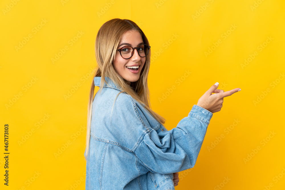 Young blonde woman isolated on yellow background pointing finger to the side Young blonde woman isolated on yellow background pointing finger to the side
