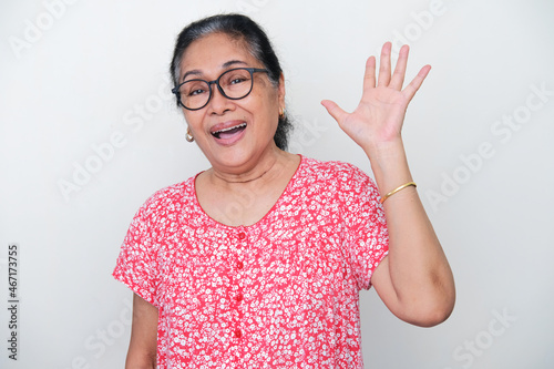 Elderly Asian woman waving her hand to greet someone photo