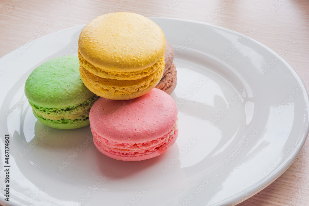Close up colorful macarons cakes. Macaroons isolated on a white plate. 
A french sweet delicacy.