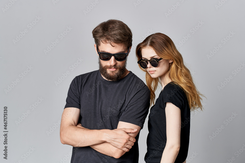 a young couple in black t-shirt sunglasses posing isolated background a young couple in black t-shirt sunglasses posing isolated background