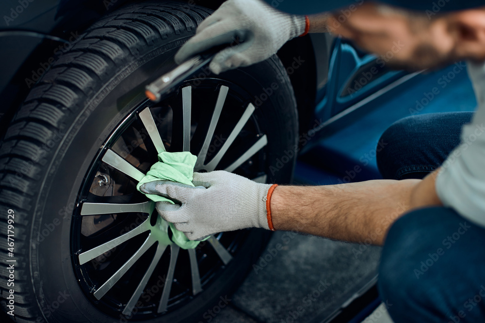 Close-up of worker cleans tire after changing it at car service workshop. Close-up of worker cleans tire after changing it at car service workshop.
