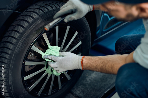 Close-up of worker cleans tire after changing it at car service workshop.