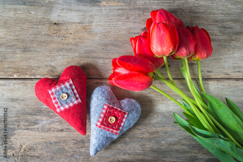 Fototapeta Naklejka Na Ścianę i Meble -  Happy Valentine's day greeting card; two handmade hearts and bouquet of red tulips on old wooden background; copy space, flate lay
