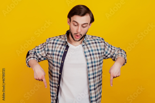 Photo of young attractive man amazed look point fingers empty space advert attention isolated over yellow color background