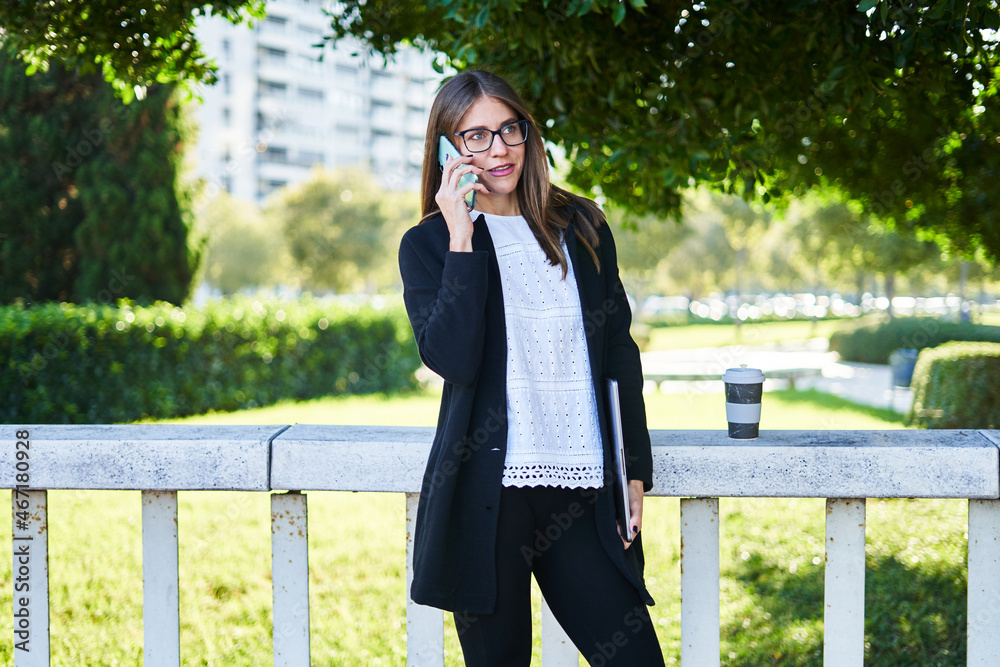 Busy businesswoman with laptop talking on smartphone Busy businesswoman with laptop talking on smartphone