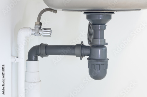Drain pipe or sewer under kitchen sink. Pvc plastic pipe and flexible supply tube connection to stainless steel sink include faucet, trap for drain water and waste in drainage and plumbing system.