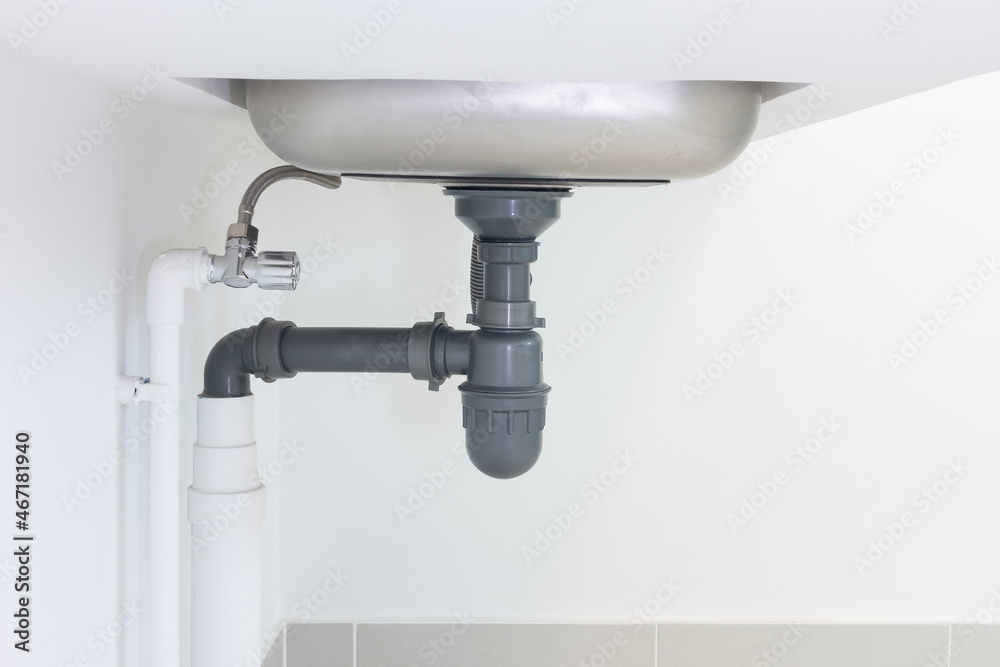 Drain pipe or sewer under kitchen sink. Pvc plastic pipe and flexible  supply tube connection to