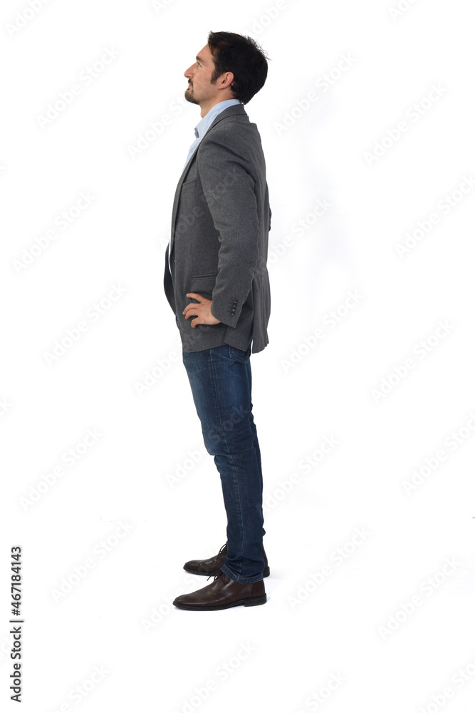 side view of a man with blazer and jeans hands on hip looking up on white background side view of a man with blazer and jeans hands on hip looking up on white background