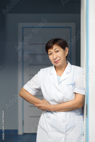 Vertical portrait of a senior female doctor in middle asian Kazakhstan clinic interior.