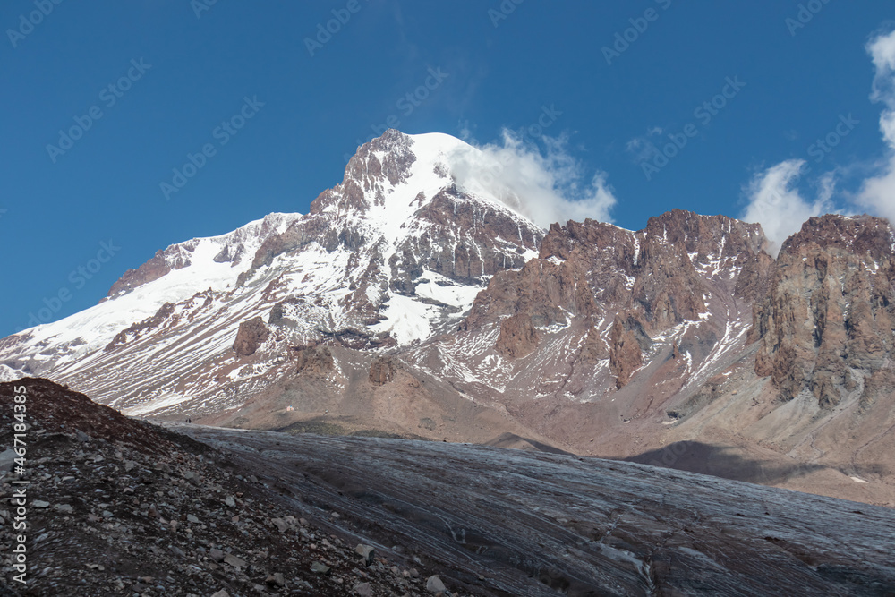 A cloudless view on Mount Kazbeg in Caucasus, Georgia. There slopes are barren and stony below the snow-capped peak and the Gergeti Glacier. Tranquillity. Natural remedy. Massive glacier foot