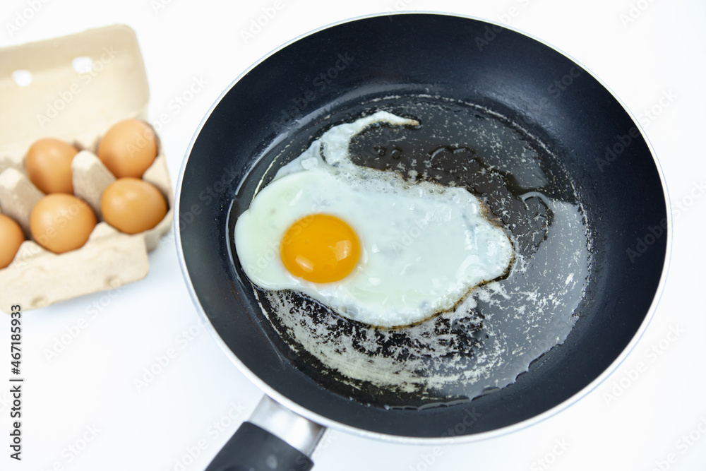 Fry eggs in an old pan and there are a number of eggs in a box on a white background. Fry eggs in an old pan and there are a number of eggs in a box on a white background.
