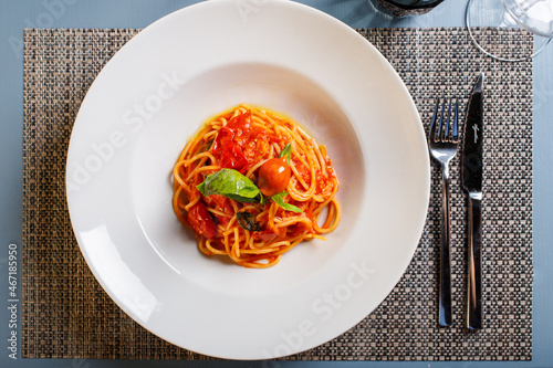 Spaghetti con sugo di pomodoro e basilico fresco serviti in un ristorante come primo piatto photo