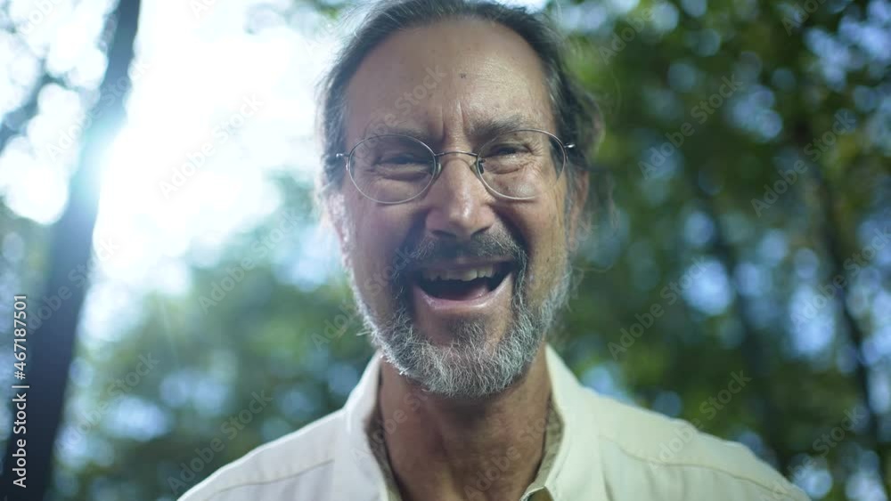 Backlit closeup portrait of ethnic man with glasses smiling and laughing and looking at camera with sun. Backlit closeup portrait of ethnic man with glasses smiling and laughing and looking at camera with sun.