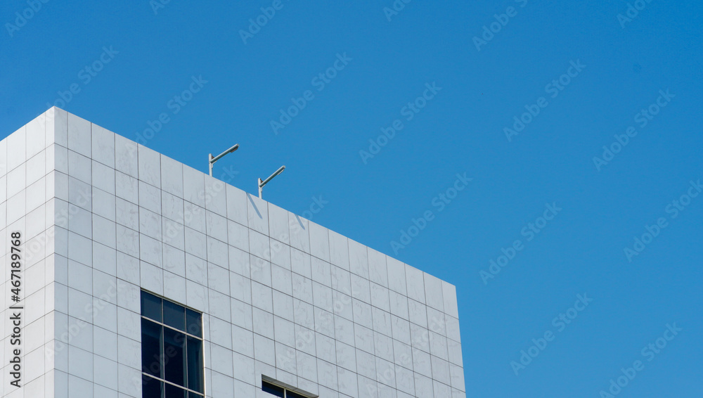 Obraz premium a skyscraper building that has a white ceramic wall with a blue sky background. the high building in the urban area.