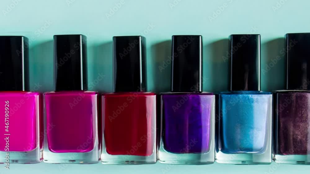 Group of bright colored nail polishes on blue background. Set of decorative cosmetics for body care. Group of bright colored nail polishes on blue background. Set of decorative cosmetics for body care.