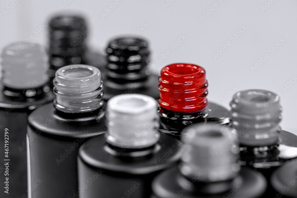 Bottles with gel varnishes for manicure and pedicure close-up. Black and white photo with a red accent. Materials for a beauty salon. Horizontal photo. Bottles with gel varnishes for manicure and pedicure close-up. Black and white photo with a red accent. Materials for a beauty salon. Horizontal photo.