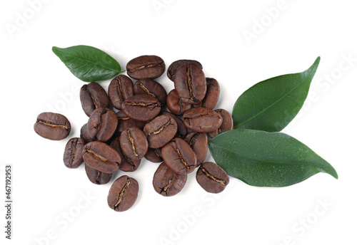 Pile of roasted coffee beans with fresh leaves on white background, top view