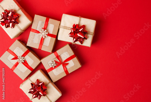 Christmas, New Year's background. Gifts in kraft paper and kraft boxes with red ribbon and bows on a red background