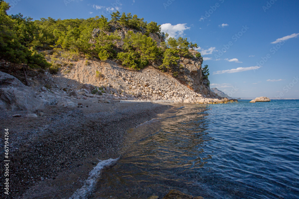 Wild beach in the village of Beldibi in Turkey. The rocks hang over the sea. A small bay in the Mediterranean Sea.