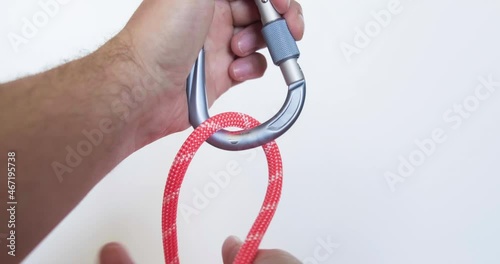 Tying a clove hitch on a carabiner using a red colored rope. This clove hitch knot used in climbing is called Mastwurf in German and Noeud de cabestan in French. photo