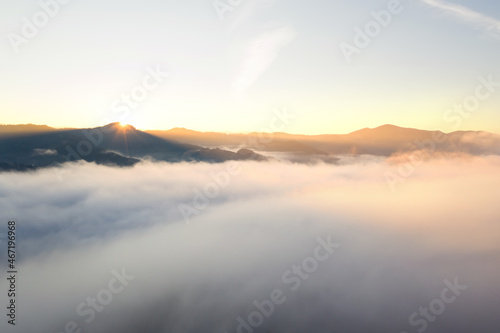 Aerial view of beautiful mountains covered with fluffy clouds at sunrise. Drone photography © New Africa