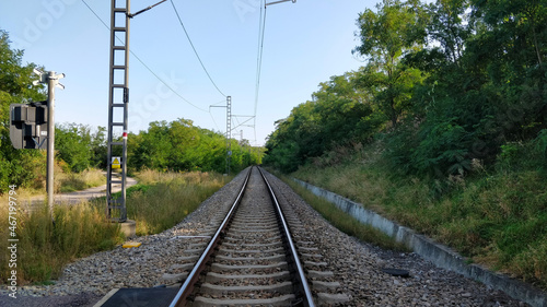 Railroad goes through the beautiful nature of South Moravia. The track is lined with electric power poles. The viewer stands on road crossing.
