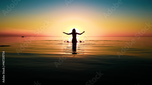 silhouette of a girl with raised hands in the water against the background of the sun disk during a colored sunset