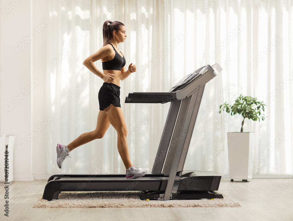 Fit young woman running on a treadmill at home Fit young woman running on a treadmill at home