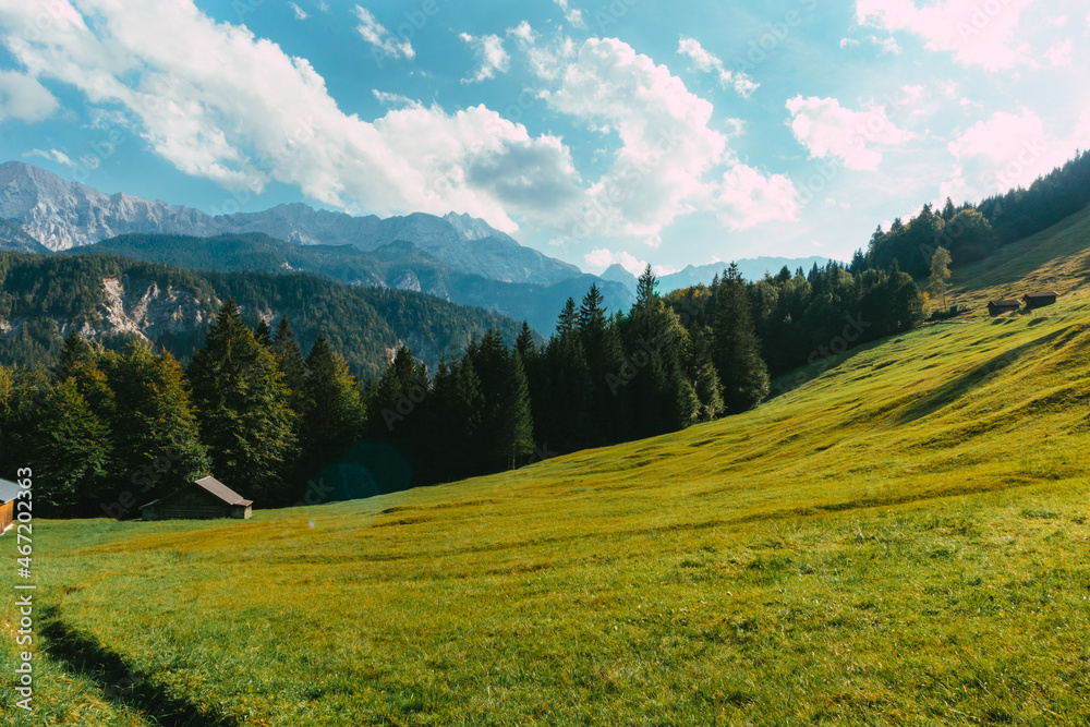 View from a grassy hill over the mountains during a sunny day